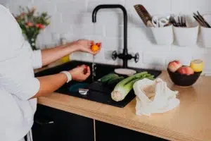 A woman is washing at a kitchen sink with a faucet
