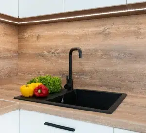 Black single-hole kitchen sinks and faucets with vegetables beside them